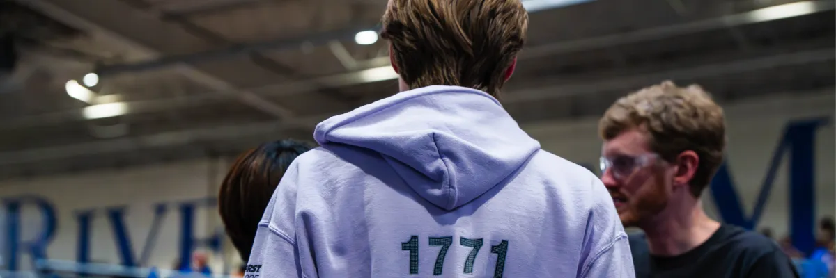 Logan at a robotics event, wearing a 1771 hoodie and seen from behind